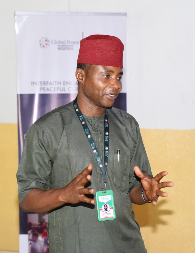 A man in a green shirt receiving mediation training for conflict prevention.