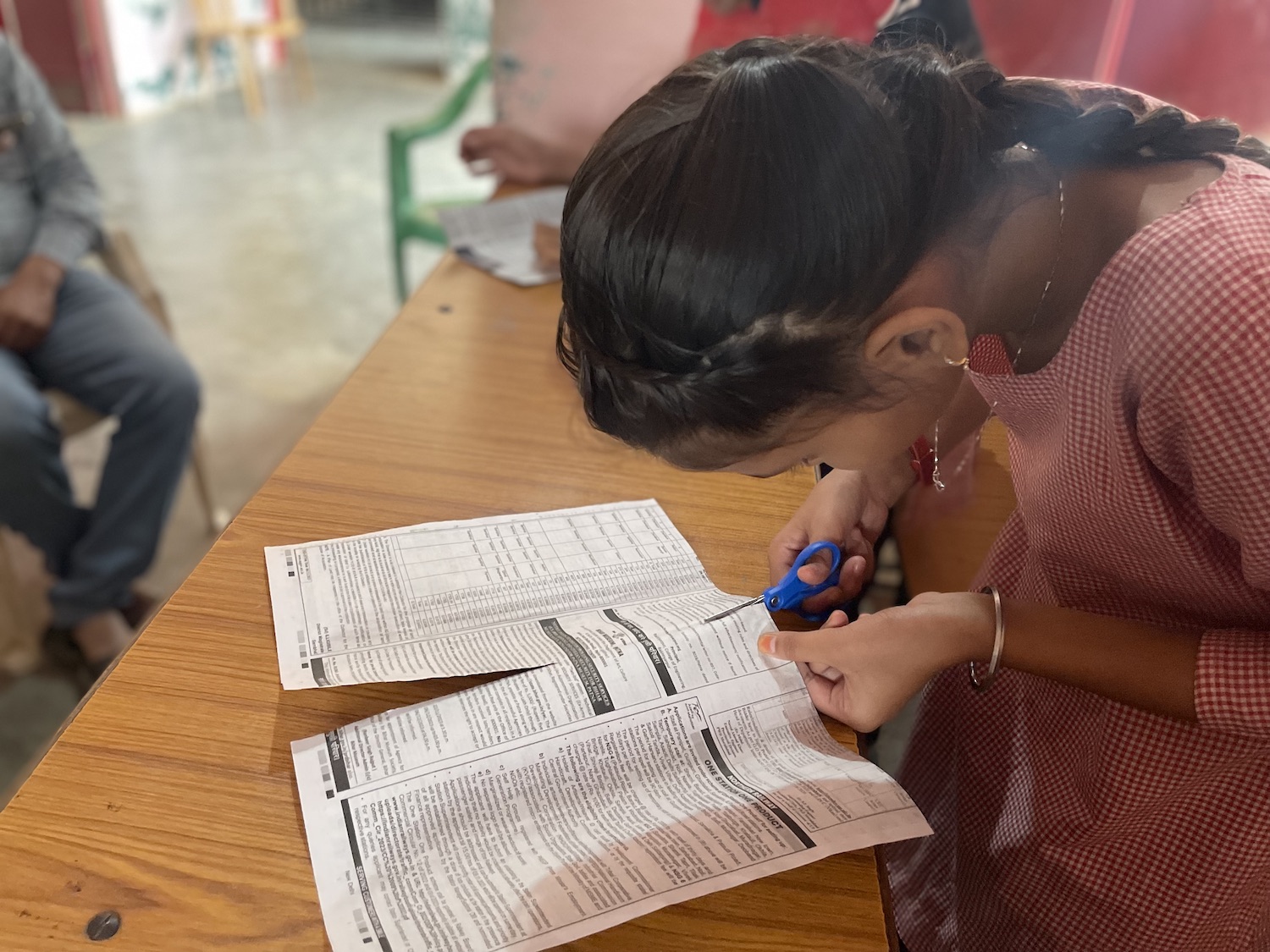 Cutting recycled material A girl filling out a form in front of a group of people celebrating Diwali, the Festival of Lights.