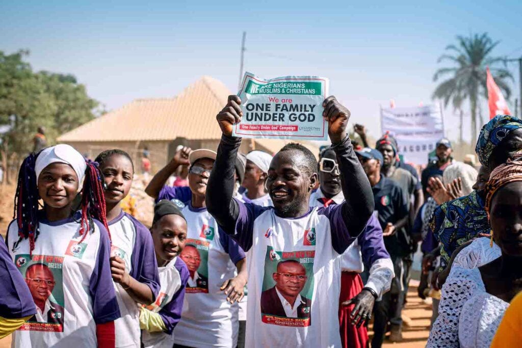 A group of people from Nigeria holding up a sign promoting community peace.
