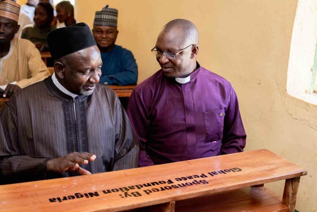 Two men standing in front of a Bukuru wooden box.