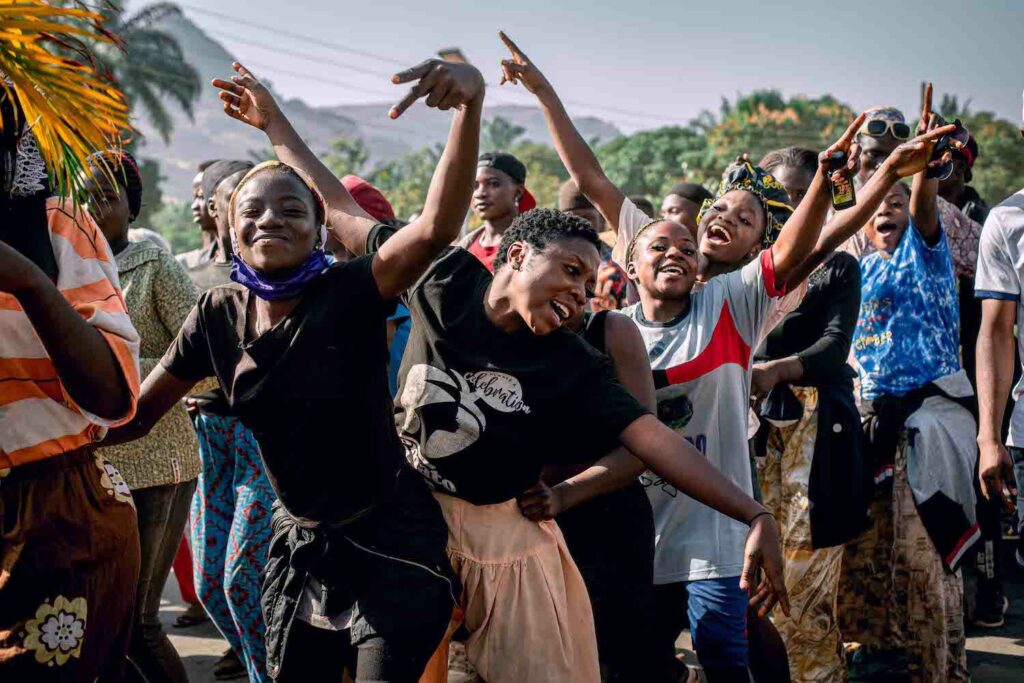 A community of people in Nigeria, united in peace and joy, raising their arms up in the air.