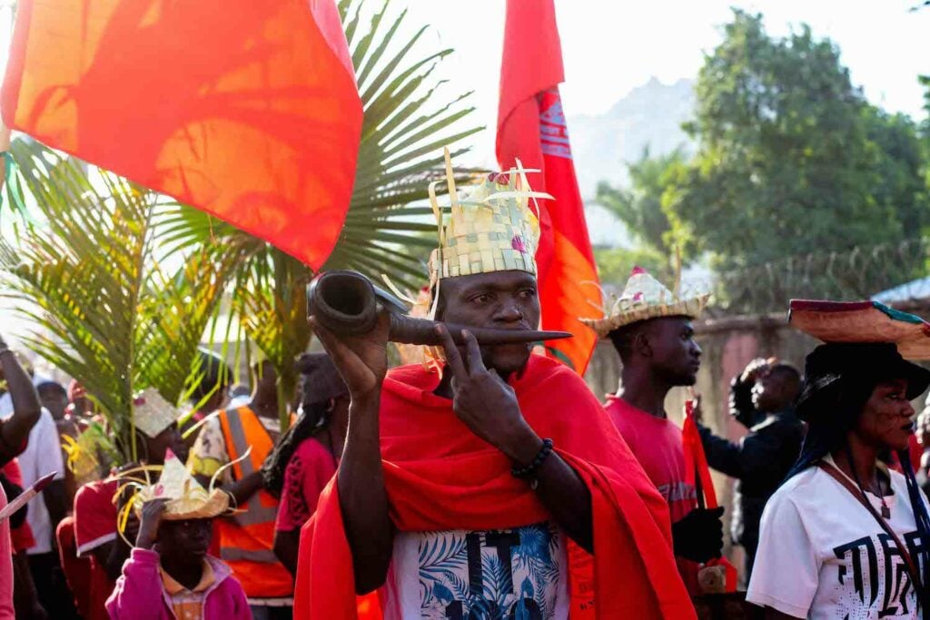 A man in a red robe from Nigeria, sustaining community peace.