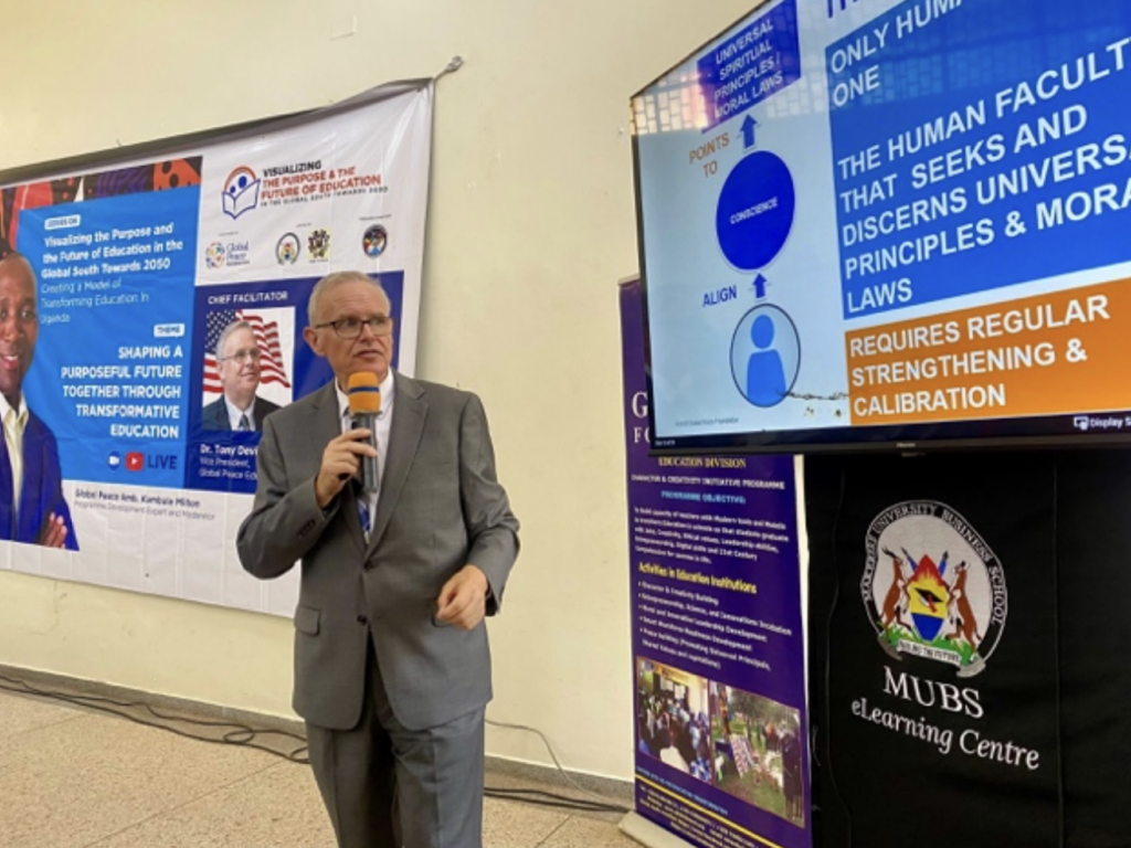 A man presenting at an educational conference on Transformative Education with informational banners in the background.