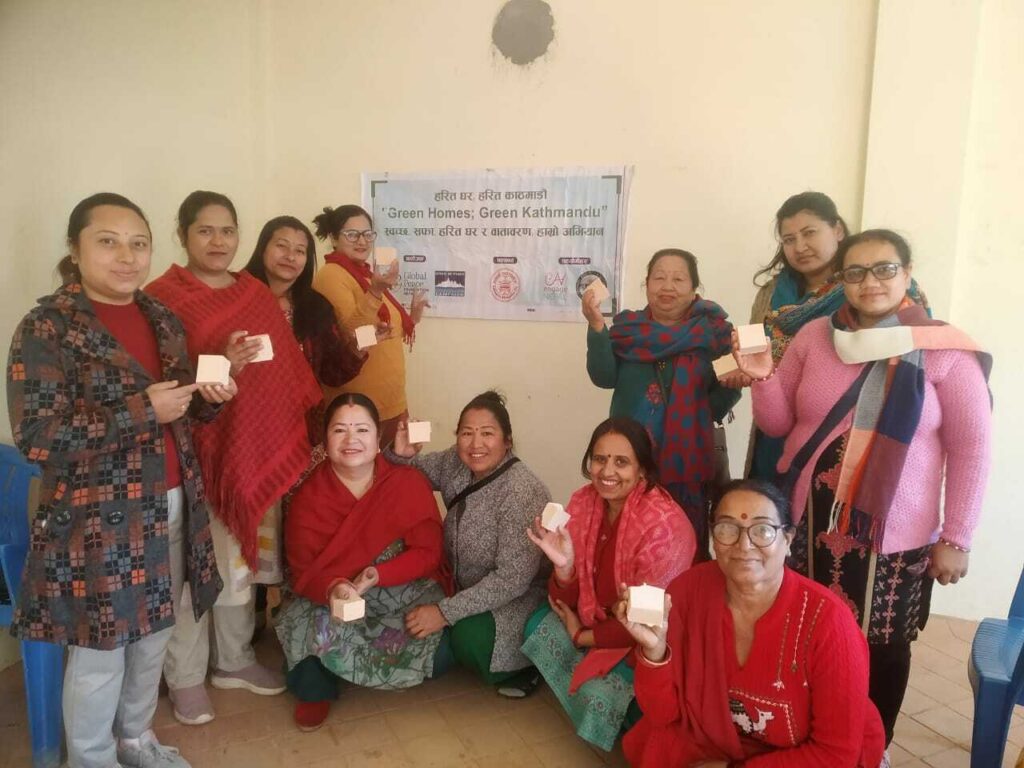A group of environmentally-friendly women holding up small white boxes, standing in front of a banner titled