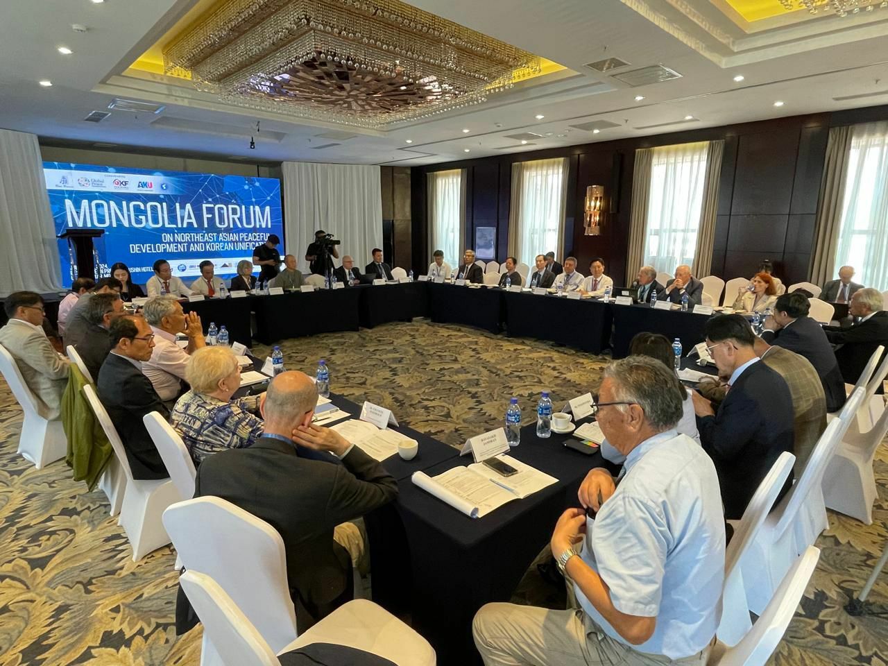 A group of people seated around a large rectangular table engaged in discussion at the Mongolia Forum, focused on infrastructure development and sustainability in Northeast Asia.