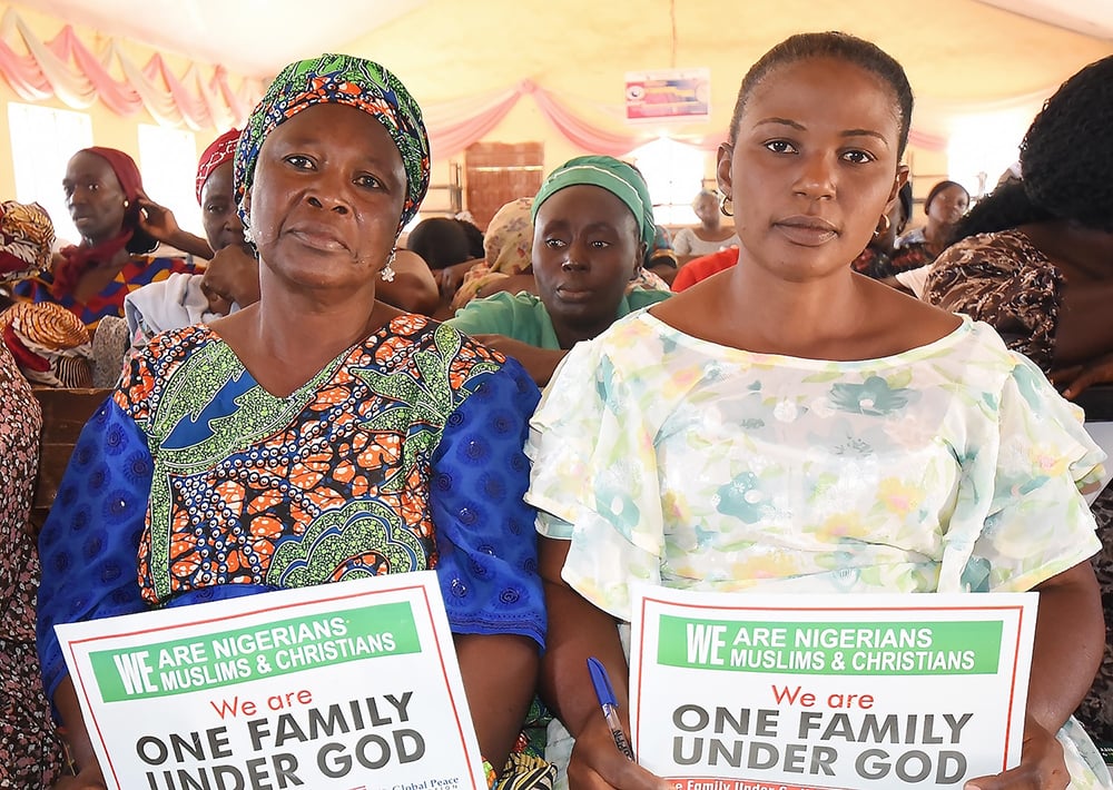 Two women hold signs reading