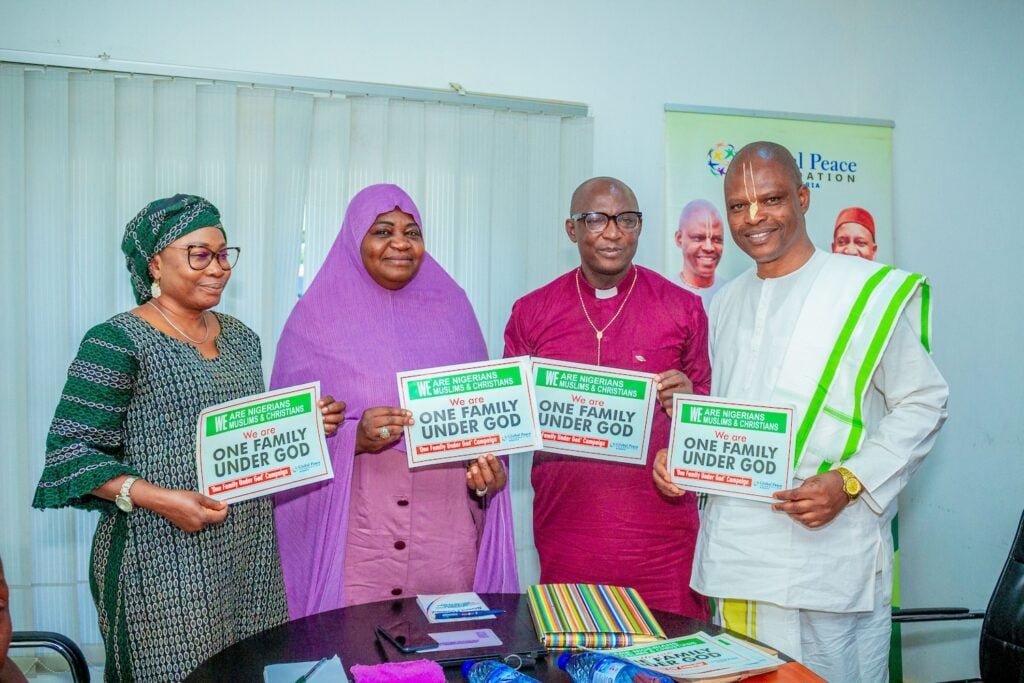 In an office setting, four people stand united, holding signs that declare 