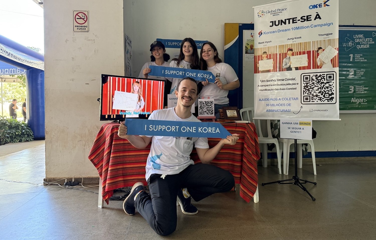 Five people at an indoor booth promote the